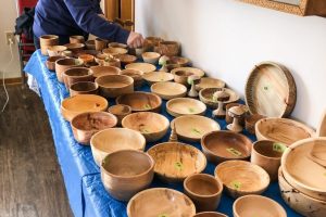 man a table with filled with turned bowls