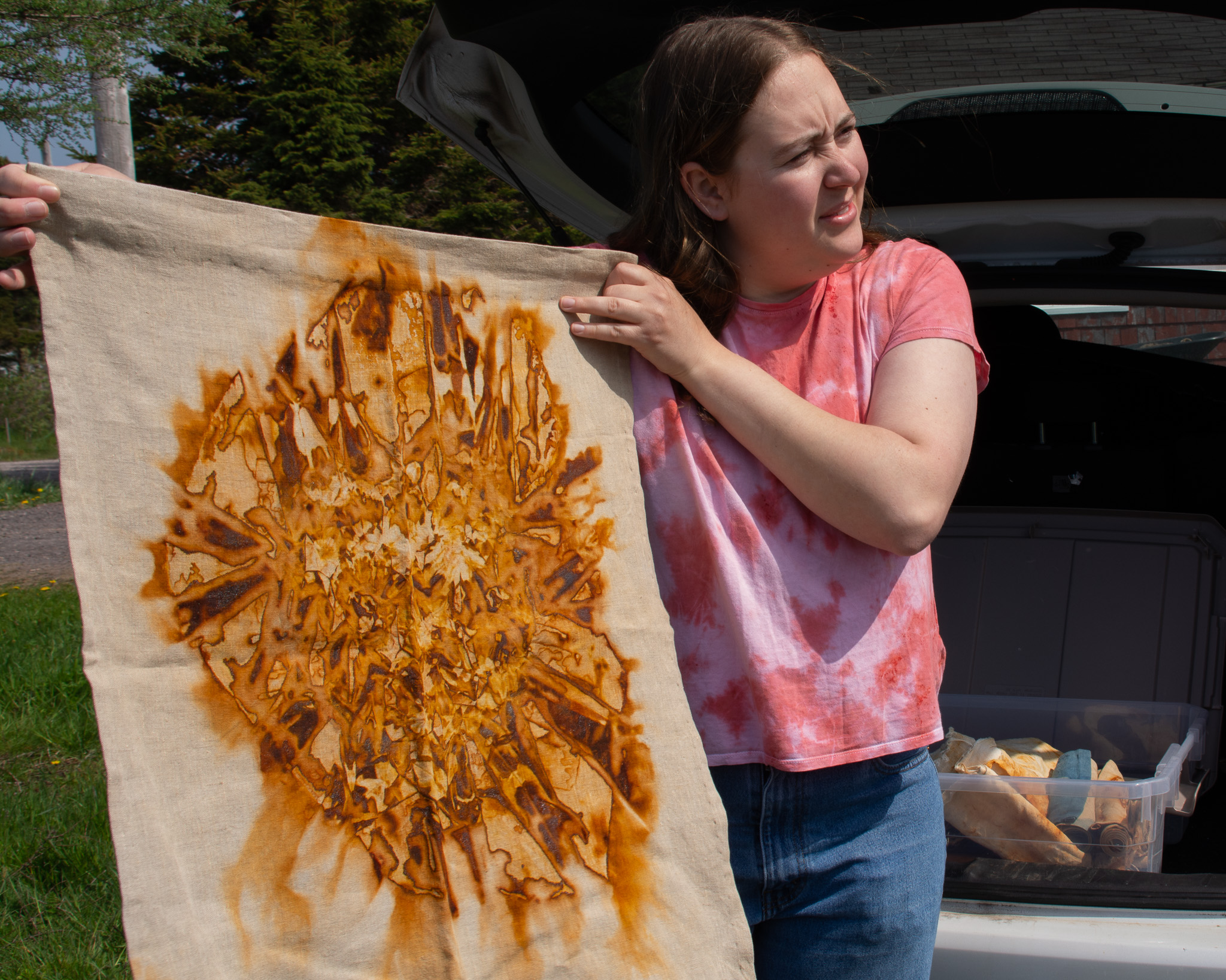 woman displaying her textile art behind her car