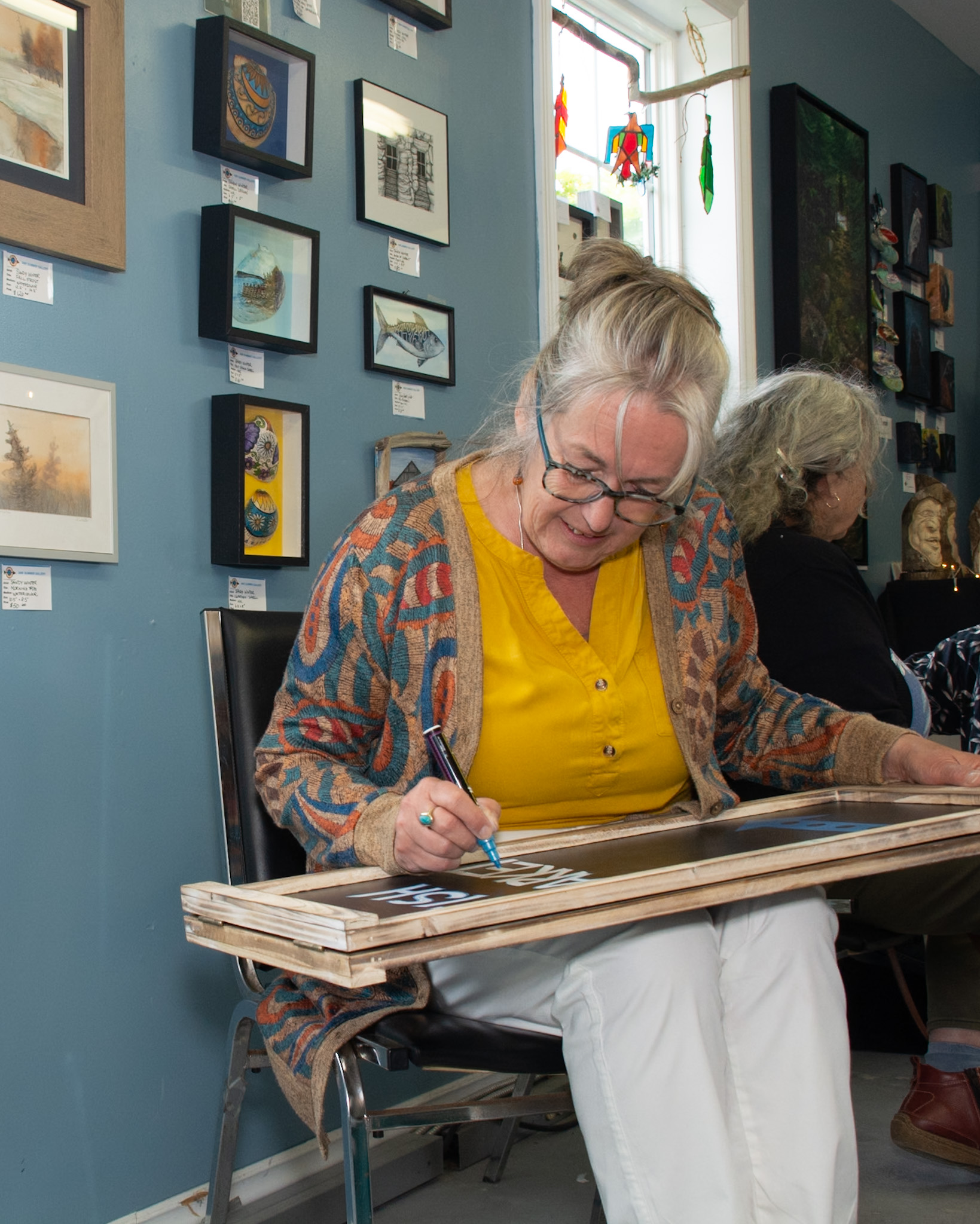 Founding member Sandy Winter is a painter. Behind her are some of her smaller pieces. She's shown here working on a sign for the gallery's new neighbour, the fish market. It's pretty handy when you're starting up a shop and your neighbours are artists.